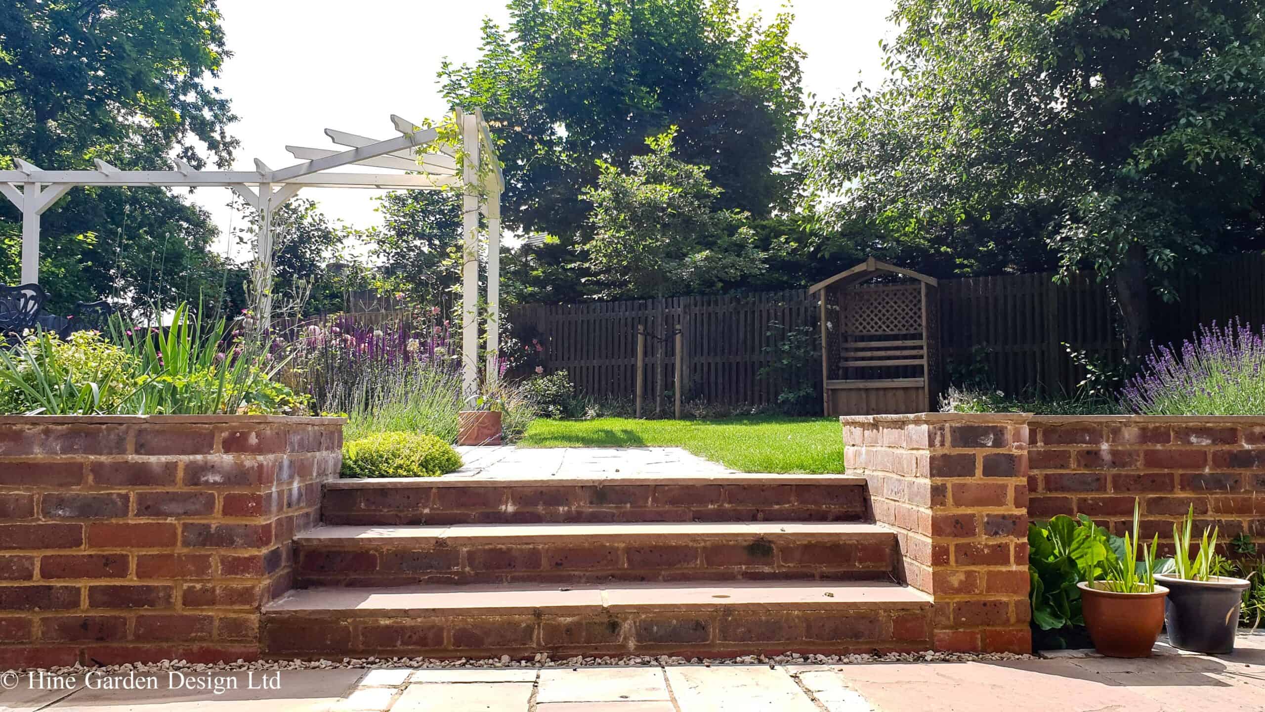 designed steps in garden wall with planting and corner pergola